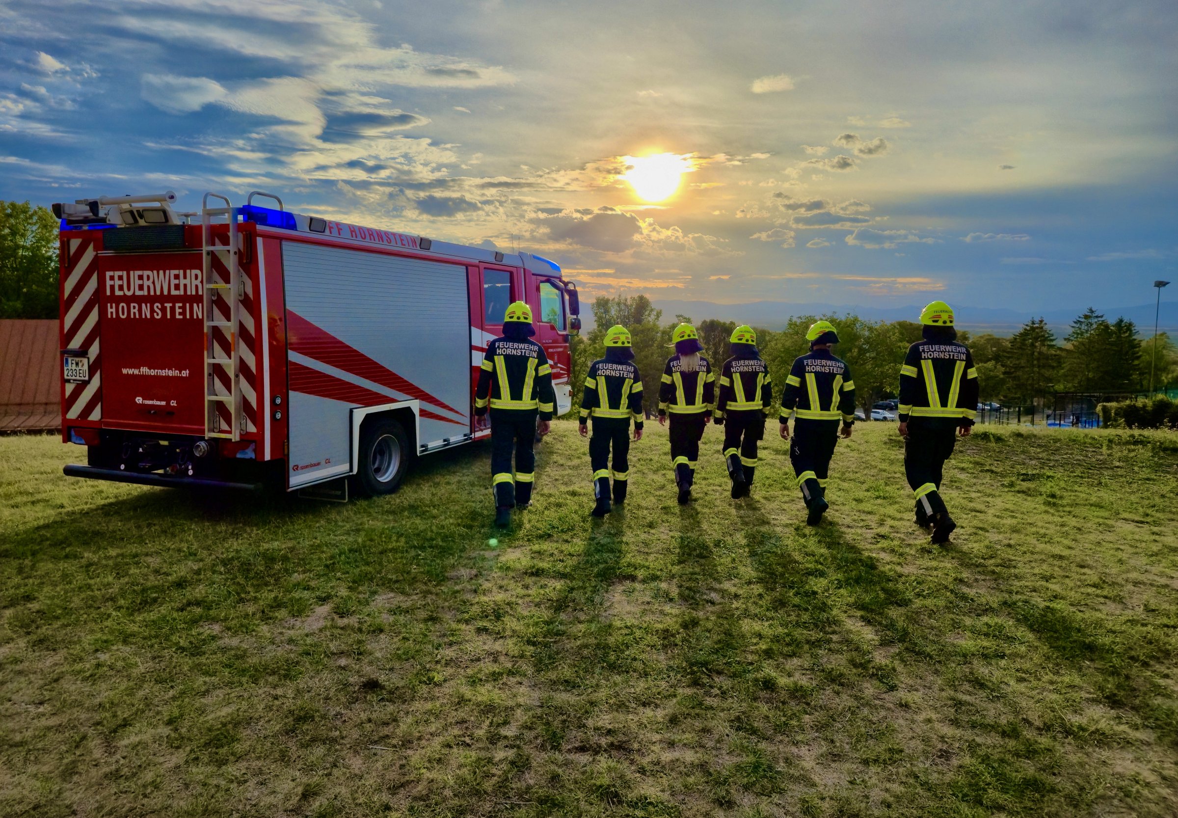 Einsatzfahrzeug und Mannschaft der Freiwilligen Feuerwehr Hornstein bei Sonnenuntergang